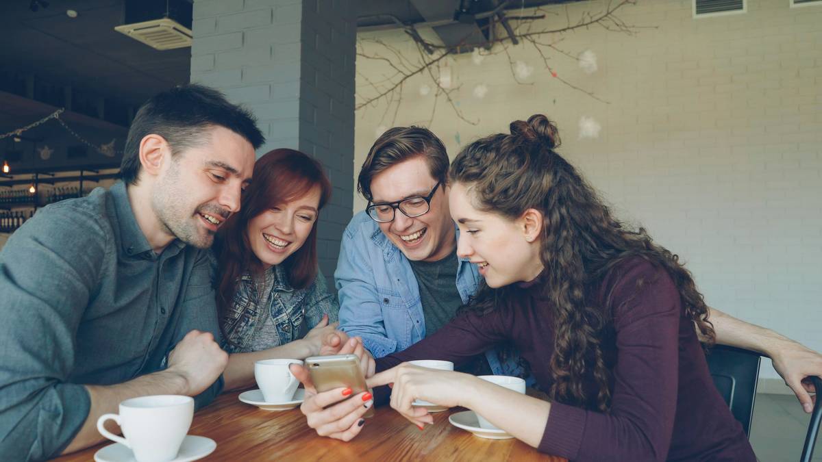 Two players coordinating strategy in a multiplayer handheld gaming friends session on smartphones