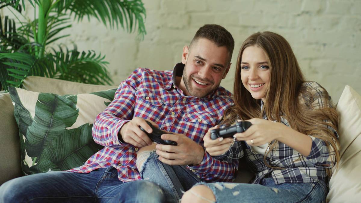 Group of friends laughing while playing multiplayer handheld gaming friends on mobile devices outdoors